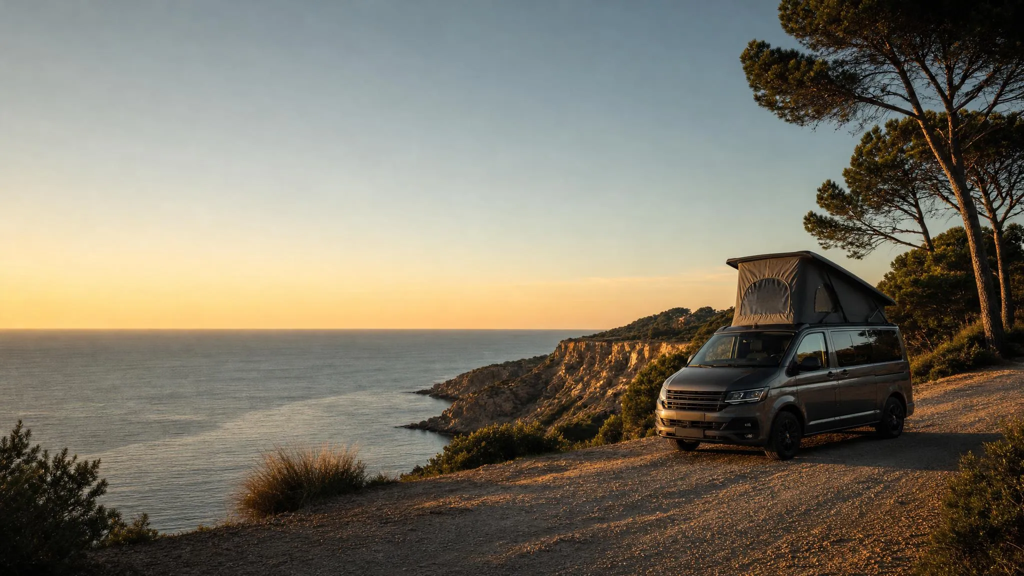 Furgoneta camper con techo elevado aparcada en los acantilados del Garraf al atardecer